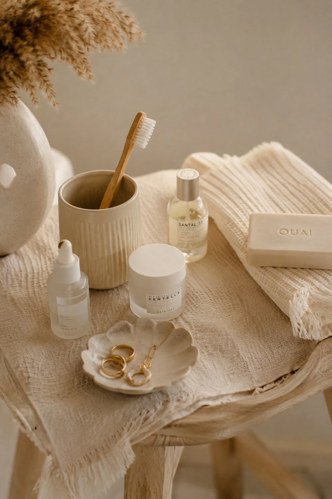 Neutral vanity with skincare bottles, a ceramic cup and linen towel