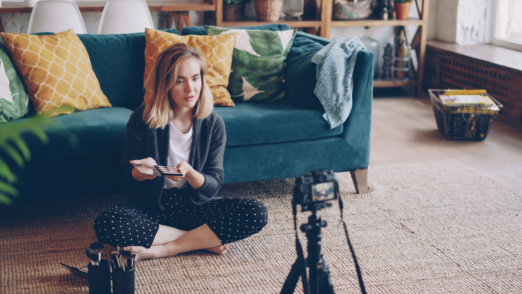 Beauty creator filming a makeup tutorial at home with a camera on a tripod