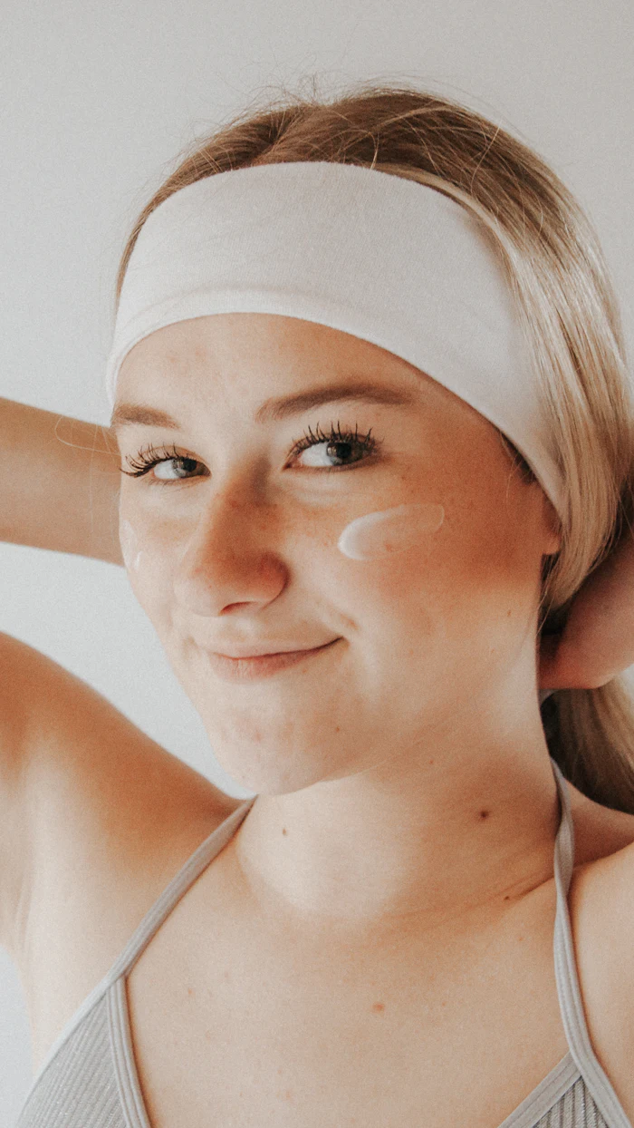 Smiling woman wearing a white headband during her skincare routine